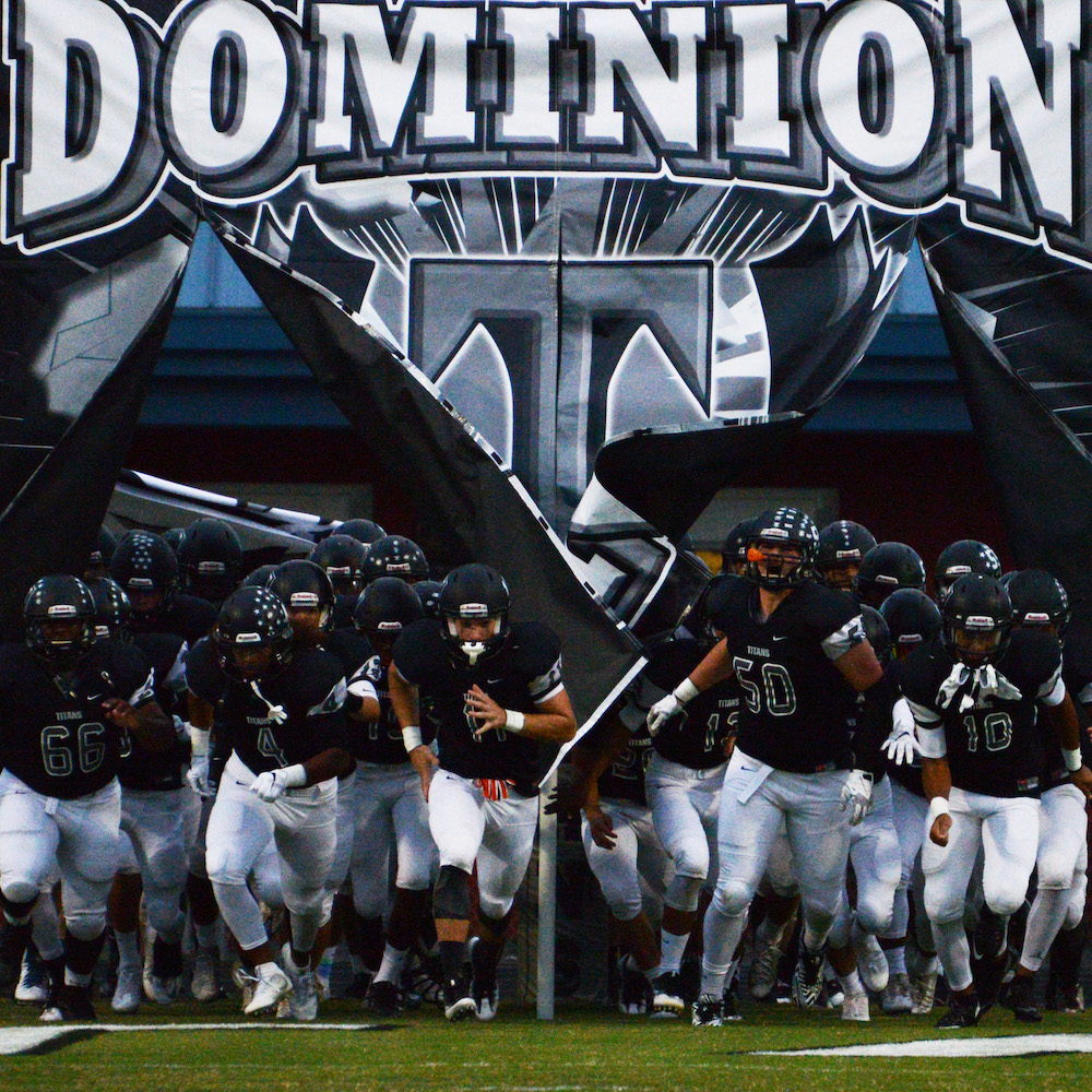 Dominion High School football players running through breakaway banner