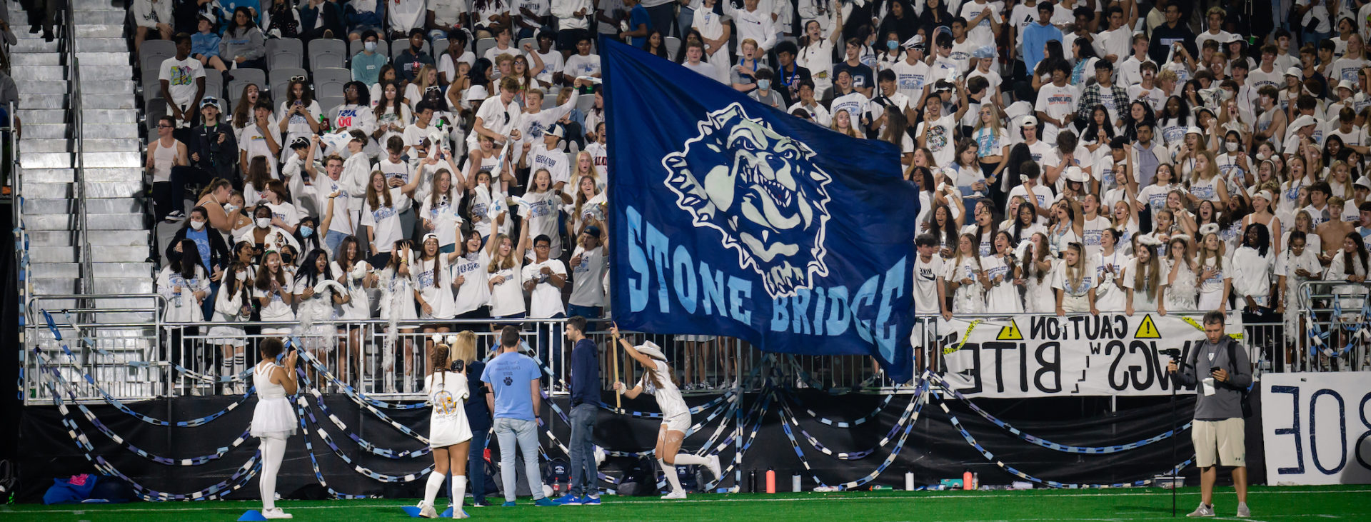 Field runner flag for Stone Bridge High School carried by cheerleader in front of crowd